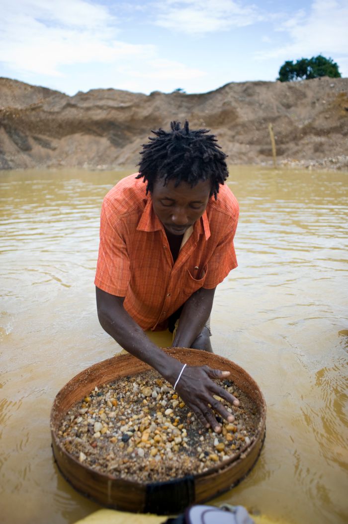 ABOUT A man processes gravel in search of diamonds in a water-filled pit, Sierra Leone.